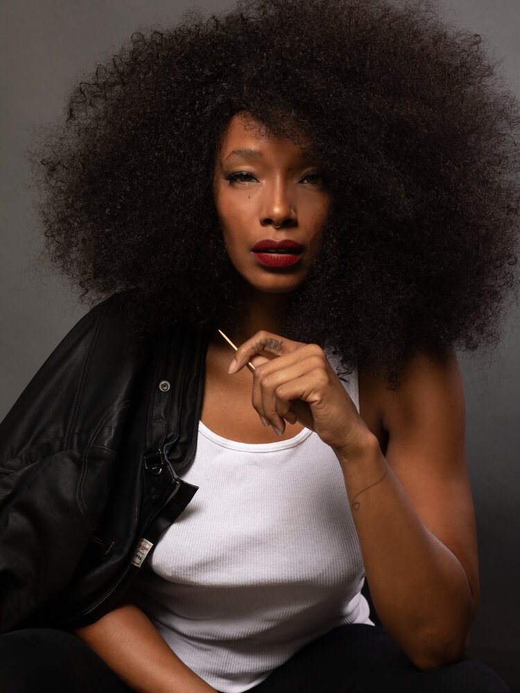 Artistic headshot of an African-American female wearing a black leather jacket and white tank top.